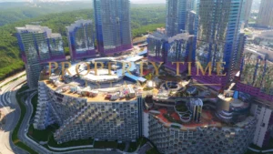 Aerial view of a crescent-shaped terraced block with a landscaped roof and glass towers behind at Maslak 1453