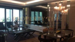 Living room with mirrored wall, marble dining table and pendant chandeliers in a Maslak 1453 apartment